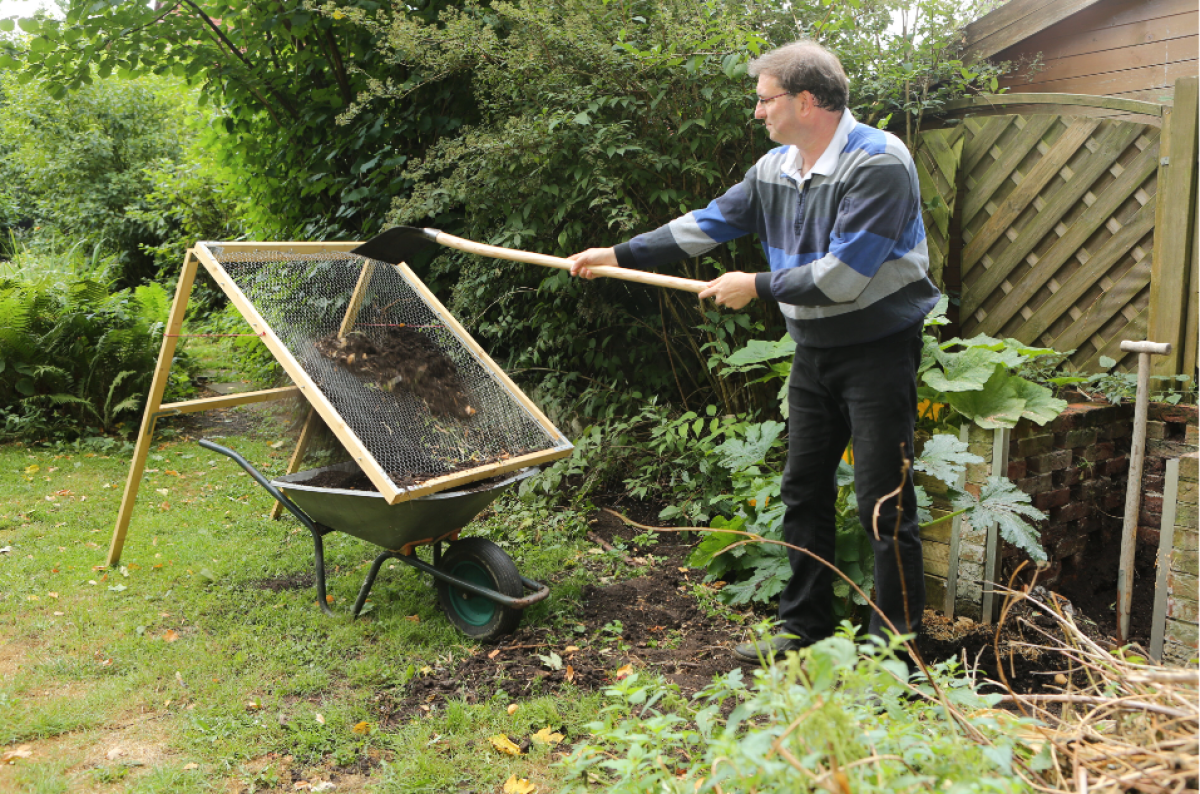 Komposzt: a kertész aranya 12 Egy férfi lapáttal átszitálja a komposztot egy rostán.