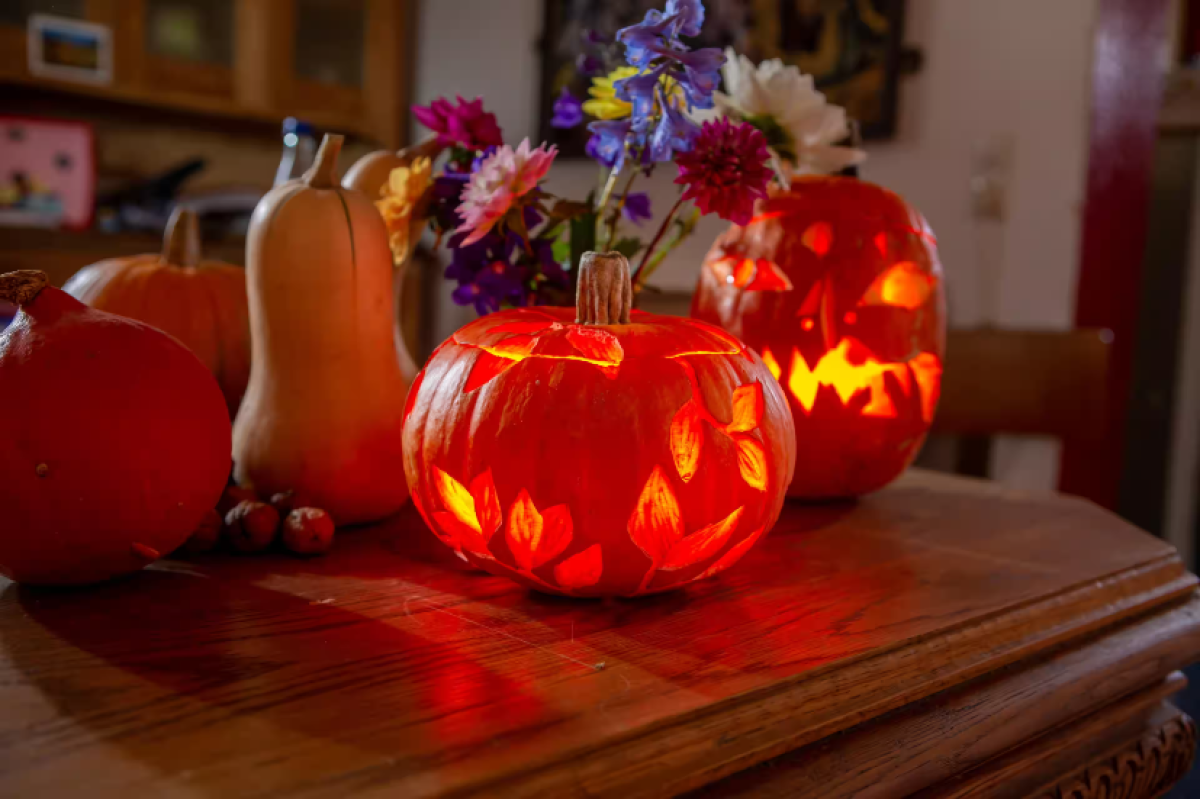 A faragott tökök az asztalon állnak és világítanak Halloween alkalmából.